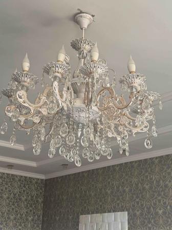 Это белая люстра в стиле барокко с хрустальными подвесками.